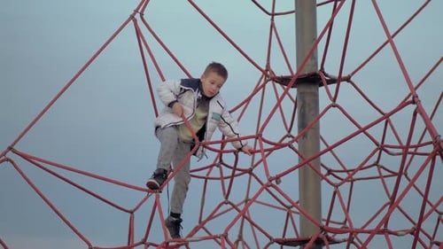 Boy Climbing on Red Rope Structure at Playground