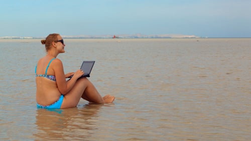 Frau benutzt Laptop im Meer