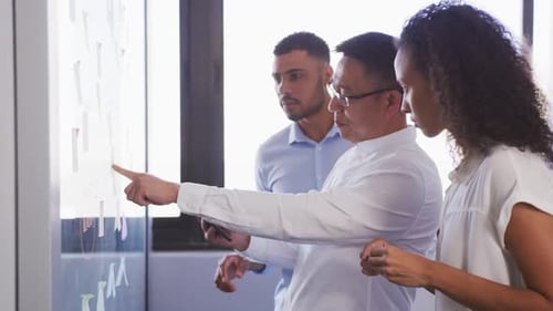 Senior Geschäftsmann mit digitalem Tablet diskutiert mit jungen Geschäftsleuten über Memo-Notizen