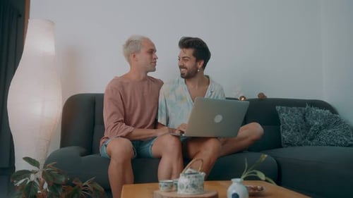 Two Young Adults Using Laptop on Couch Together