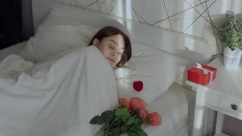 Woman Smiling in Bed with Roses and Gift