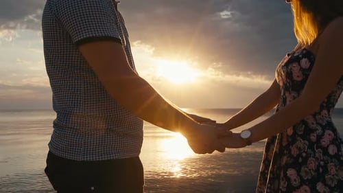 Romantic Couple Holding Hands at Sunset by the Ocean