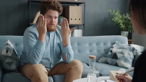 Serious Man Conversing to Therapist Discussing Life Experience Indoors in Office