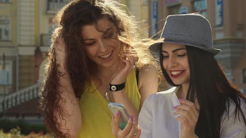 Two Friends Smiling at Smartphone in City