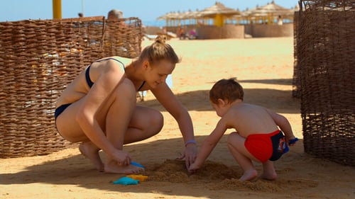 Mother and Child Playing on Beach in Summer