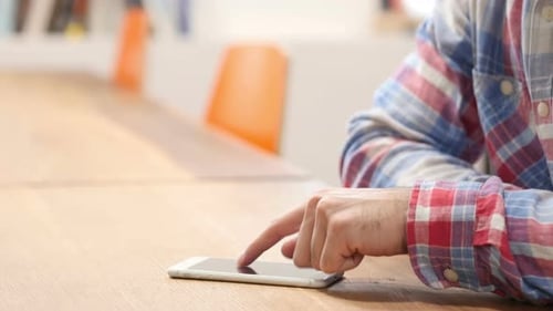 Adult Using a Smartphone on Wooden Table