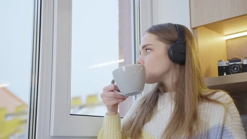 Woman with Headphones Enjoying Coffee by Window