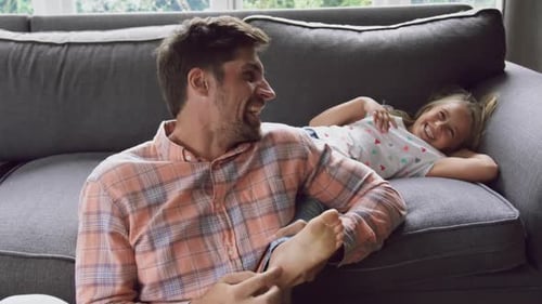 Father and daughter playing together on sofa at home 4k