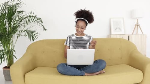Young Adult On Couch Using Laptop For Video Call