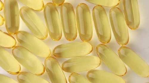 Yellow Gel Capsules on White Surface, Close Up