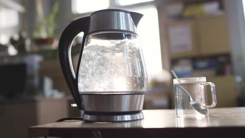 Electric Kettle Boiling Water Next to Cup