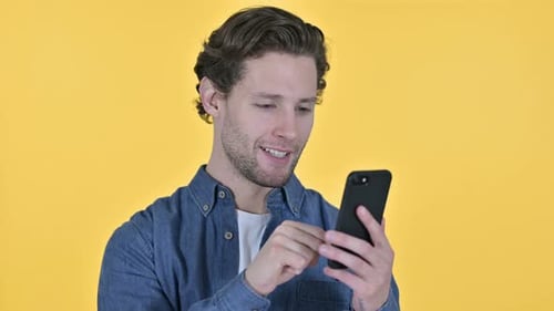 Young Man Smiles Using His Smartphone