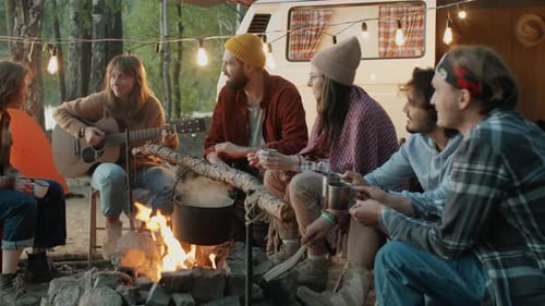 Friends Gather Around Campfire with Guitar at Campsite