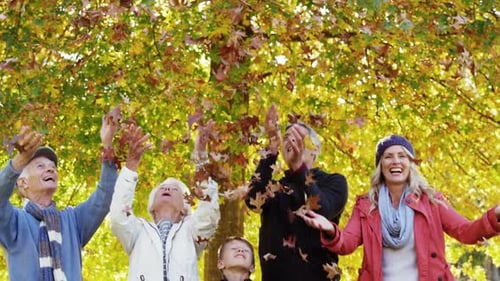 Family Throws Leaves Together in Autumn Park