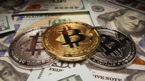 Bitcoin en or placé sur des cryptos en argent empilés sur des billets de 100 dollars