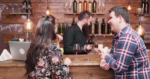 Bartender pouring wine for customers at a bar