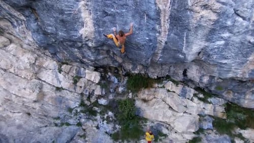 Aerial drone view of a man rock climbing up a mountain.