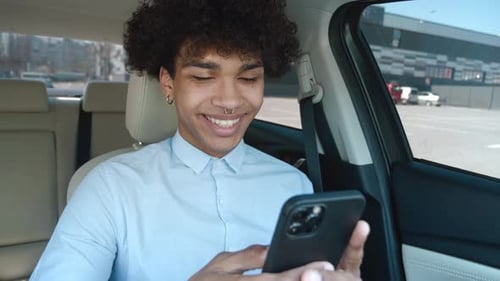 Young Adult Smiling While Using Smartphone in Car