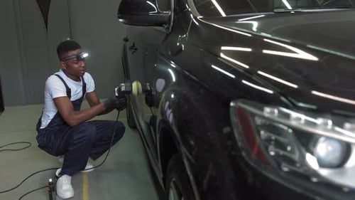 Man Polishing Black Car with Power Tool