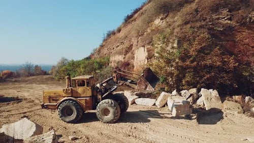 Bulldozer arbeitet in der Nähe von Sandsteinbrüchen auf dem Hintergrund von Steinen