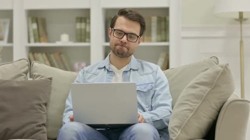 Frustrated Man Sitting on Couch With Laptop