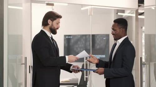 Two Smiling Businessmen Shaking Hands Together While Standing in an Office