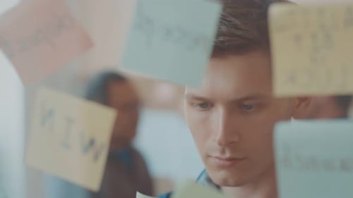 Young Man Brainstorming Ideas Using Sticky Notes