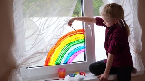 Girl Painting Colorful Rainbow on Window at Home