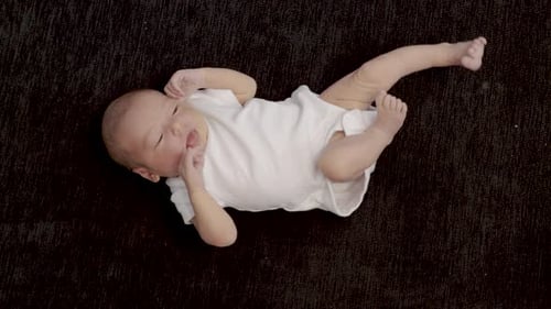 Newborn Infant Lying on Back in White Onesie