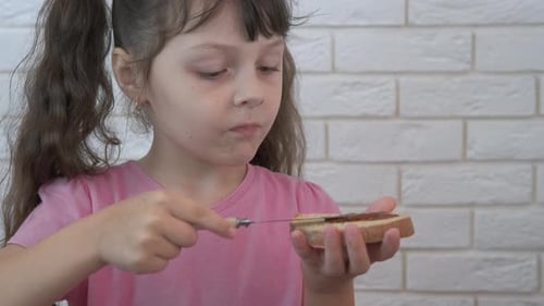 Young Girl Spreads Jam on Bread Slice