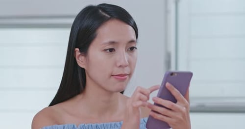 Woman Uses Smartphone and Smiles Indoors