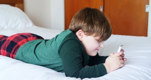 Child Playing on Cell Phone in Bed
