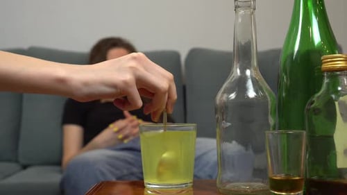 Hand Stirring Yellow Drink in Glass