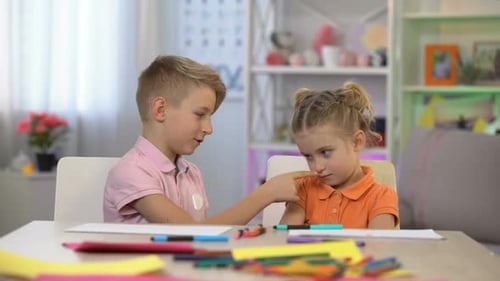 Blonde-Haired Children Drawing Together at Table Indoors