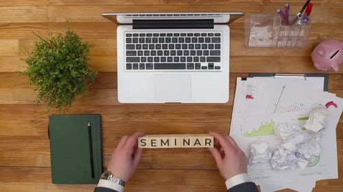 Word Seminar wird aus Holzwürfeln mit Buchstaben mit Händen auf dem Bürotisch gesammelt