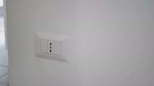 Hands Plug Black Adapter into Electrical Outlet