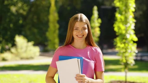 Female Student with Books in Hands Standing in Park