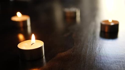 Blowing out and extinguishing four tealight candle flames and turning them to smoke in slow motion w