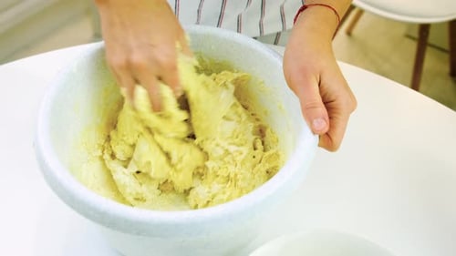 Hands Mixing Dough in White Bowl