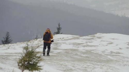 Tourist Photographer Walks on Top of a Mountain During a Heavy Snow Storm