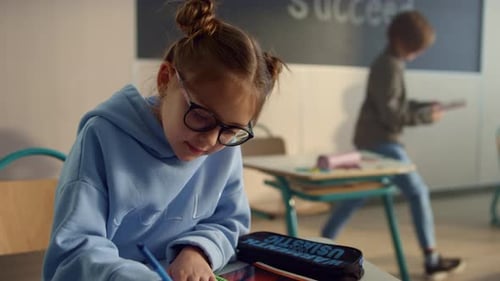 Girl Doing Schoolwork at Desk in Classroom