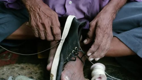 Close Up Cobbler Repairing Shoe Sole with Thread