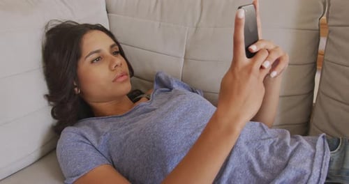 Woman Using Phone While Lying on Couch