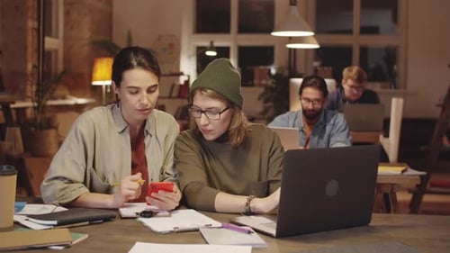 Two Young Women Coworking in Loft Office in Evening