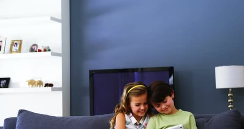 Children Using Tablet Together on Couch at Home