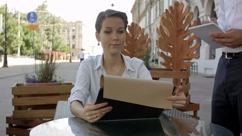 Attractive Woman Ordering To the Waiter From the Menu at the Cafe