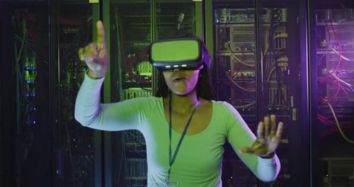 African american female computer technician using vr headset working in business server room
