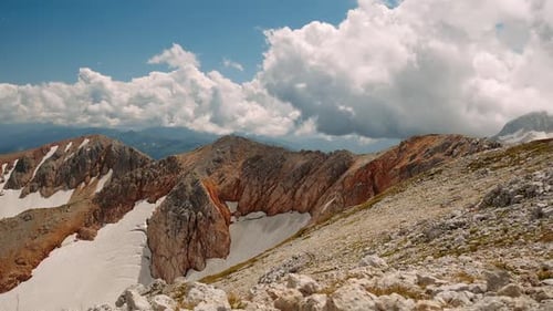 Wunderbarer Blick auf braune und graue Schneeberge im Kaukasus unter großen fliegenden Wolken im Sommer