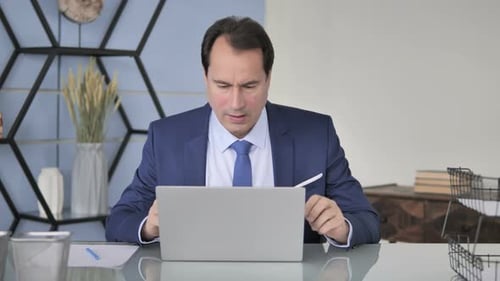 Frustrated Man in Suit Using Laptop in Office