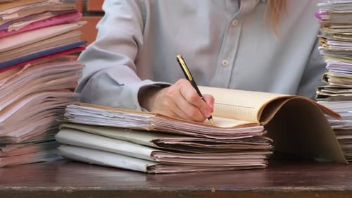 Adult Reviewing Papers and Writing Notes at Desk